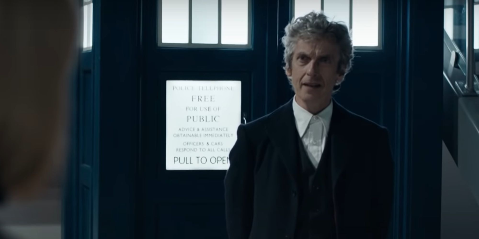 Peter Capaldi as the Twelfth Doctor in the Doctor Who spinoff Class, standing in front of his TARDIS