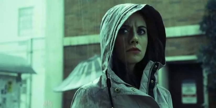 Annie em pé na chuva com um casaco com capuz na 5ª temporada de Community.