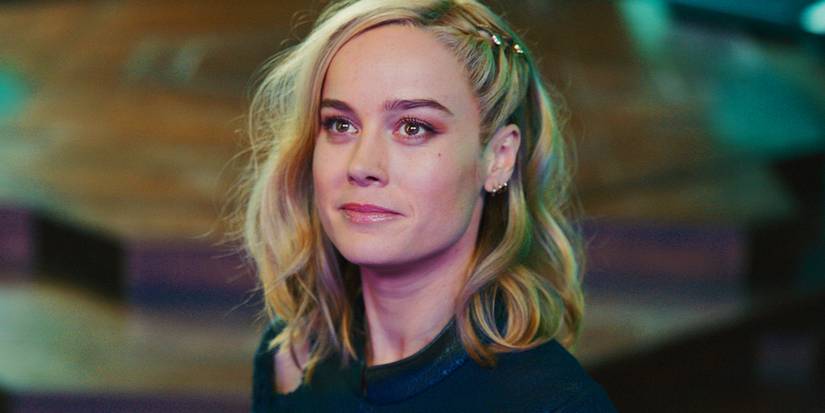 Кэрол Дэнверс/Капитан Марвел (Бри Ларсон) ухмыляется и смотрит вверх в фильме "The Marvels"