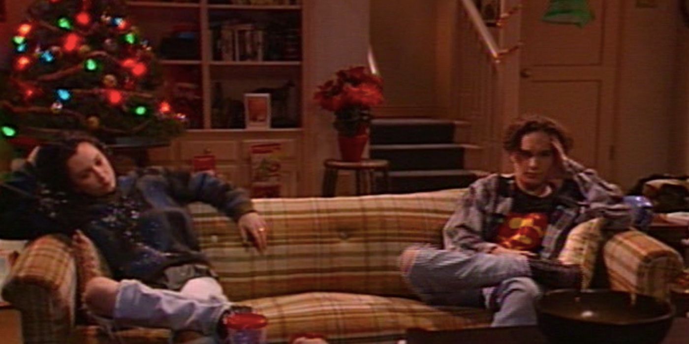 Sara Gilbert and Johnny Galecki as Darlene and David sitting on opposite ends of a couch in Roseanne season 5 episode 12