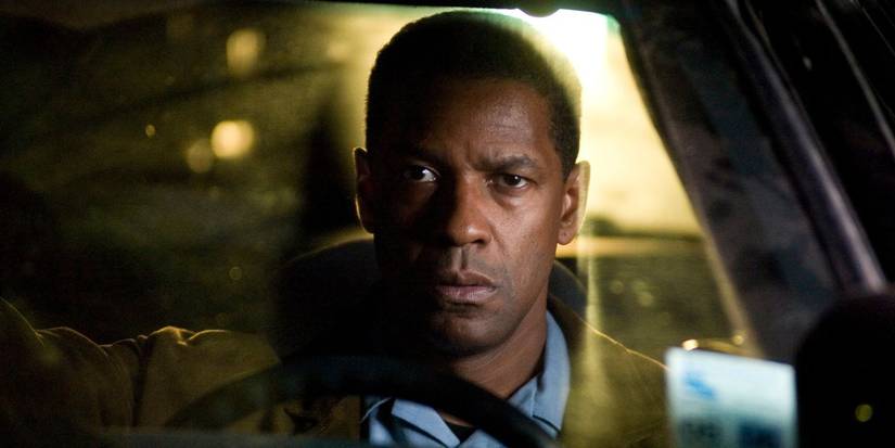 Denzel Washington as Doug Carlin sitting in a car watching someone off-screen in Déjà Vu