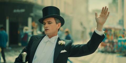 The Toymaker (Neil Patrick Harris) dances through the street wearing a tuxedo with a top hat in Doctor Who.