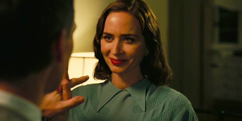 Kitty Oppenheimer (Emily Blunt) smiles and holds J. Robert Oppenheimer (Cillian Murphy)'s hand in Oppenheimer.