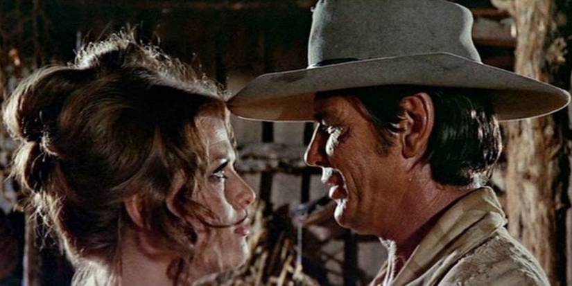 Клаудия Кардинале в роли Дил и Чарльз Бронсон в роли Хармони обнимаются и нежно смотрят друг другу в глаза в фильме "Однажды в Западном городе"