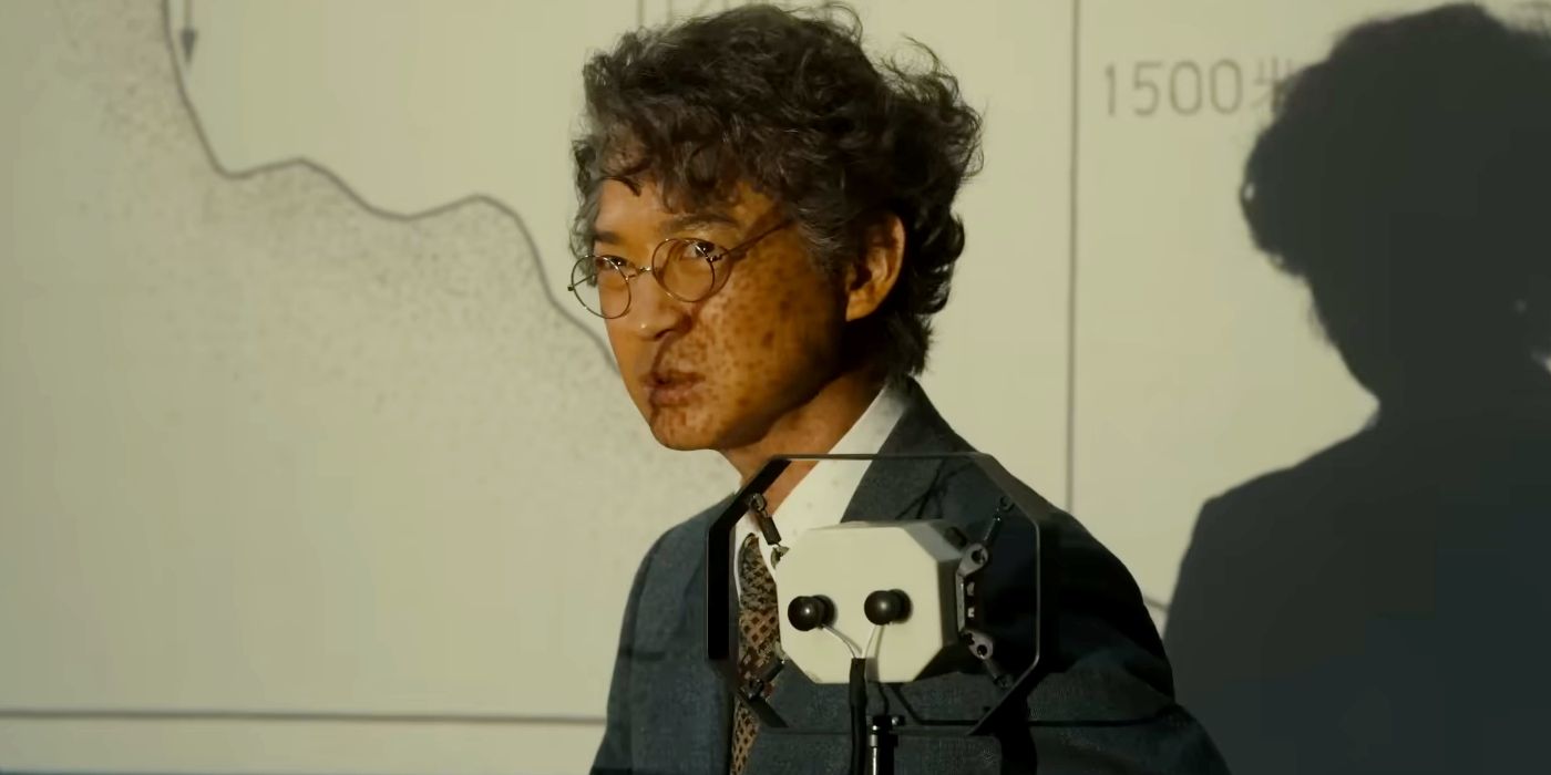 Hidetaka Yoshioka as Kenji Noda Looking Grave with a Map Projected Over His Face in Godzilla Minus One