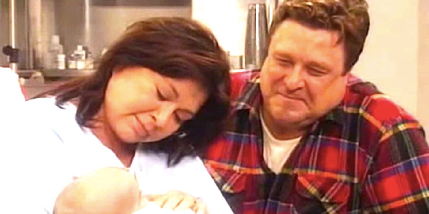 John Goodman's Dan and Roseanne Barr's Roseanne smile down at a baby in Roseanne season 8 episode 5