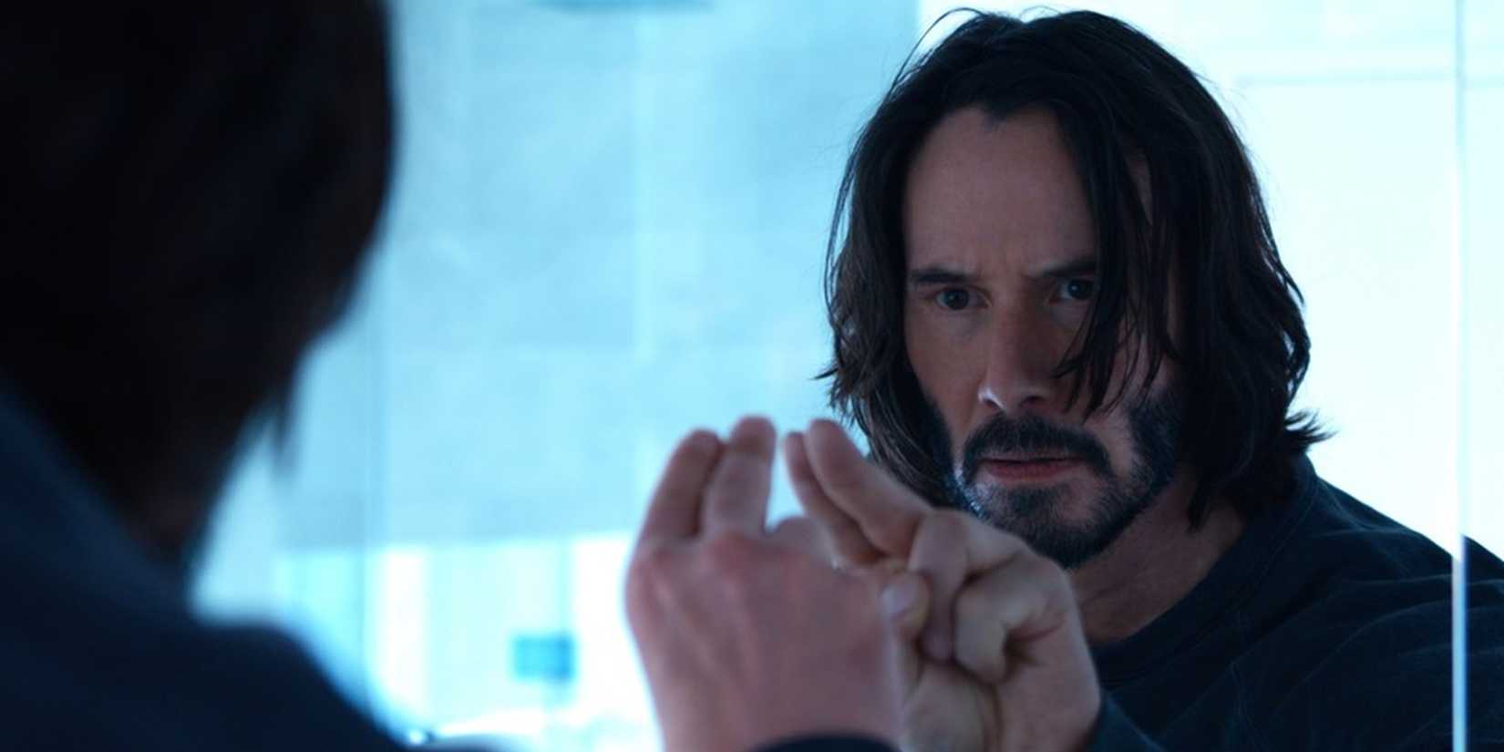 Neo looking at his reflection in a mirror in The Matrix Resurrections