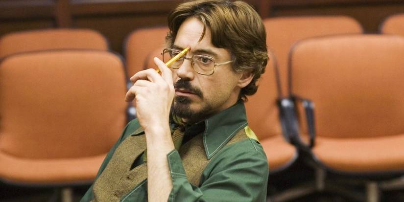 Paul Avery (Robert Downey Jr) sitting and holding a pencil to his head in Zodiac