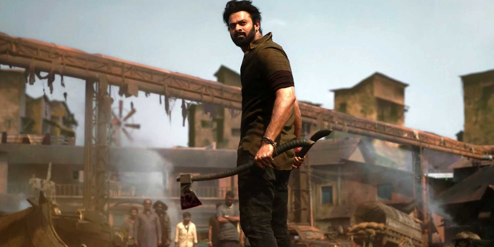 Prabhas as Salaar standing among ruins holding an axe and looking over his shoulder in Salaar Part 1 - Ceasefire.