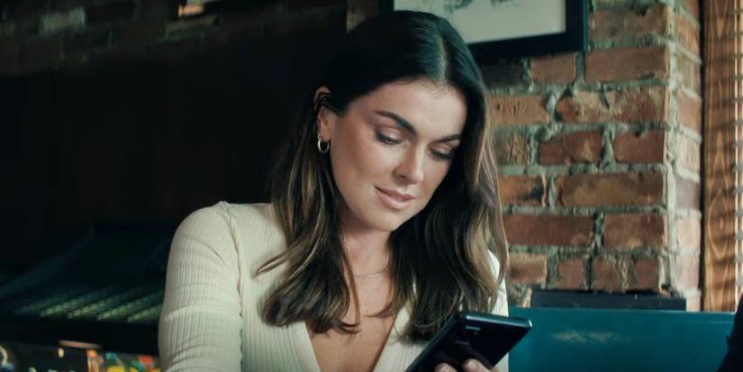 Serinda Swan as Dixon googling on her phone on Reacher season 2 episode 4