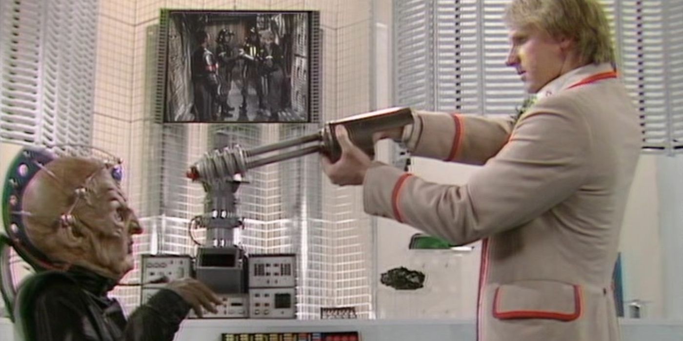 The 5th Doctor pointing a gun at Davros' head in Resurrection of the Daleks