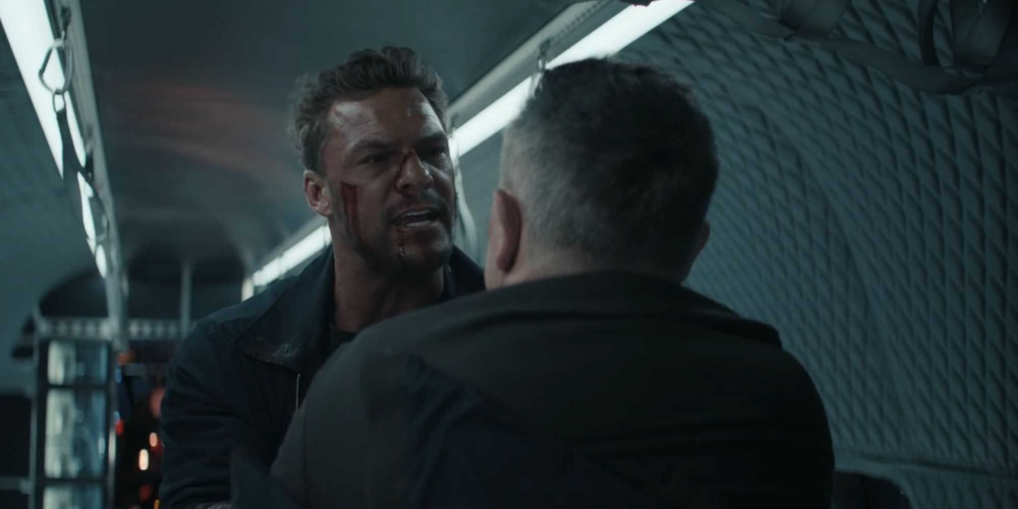 Alan Ritchson looking angry at Reacher while he holds Langston in his grasp