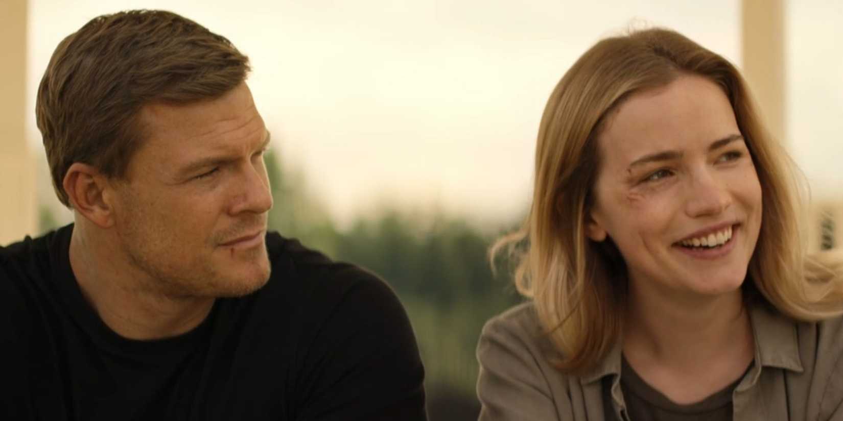 Alan Ritchson as Reacher looking at a smiling Willa Fitzgerald as Roscoe Conklin in Reacher