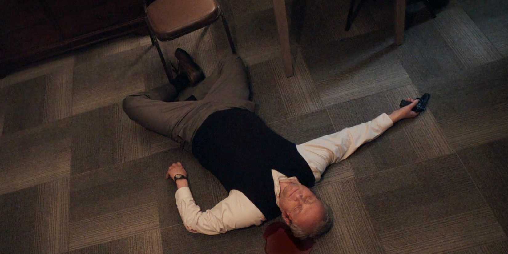 Sergei deitado no chão de seu quarto de hotel, com uma arma na mão