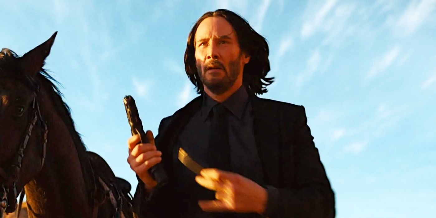 John Wick (Keanu Reeves) ricarica una pistola accanto a un cavallo in John Wick: Chapter 4