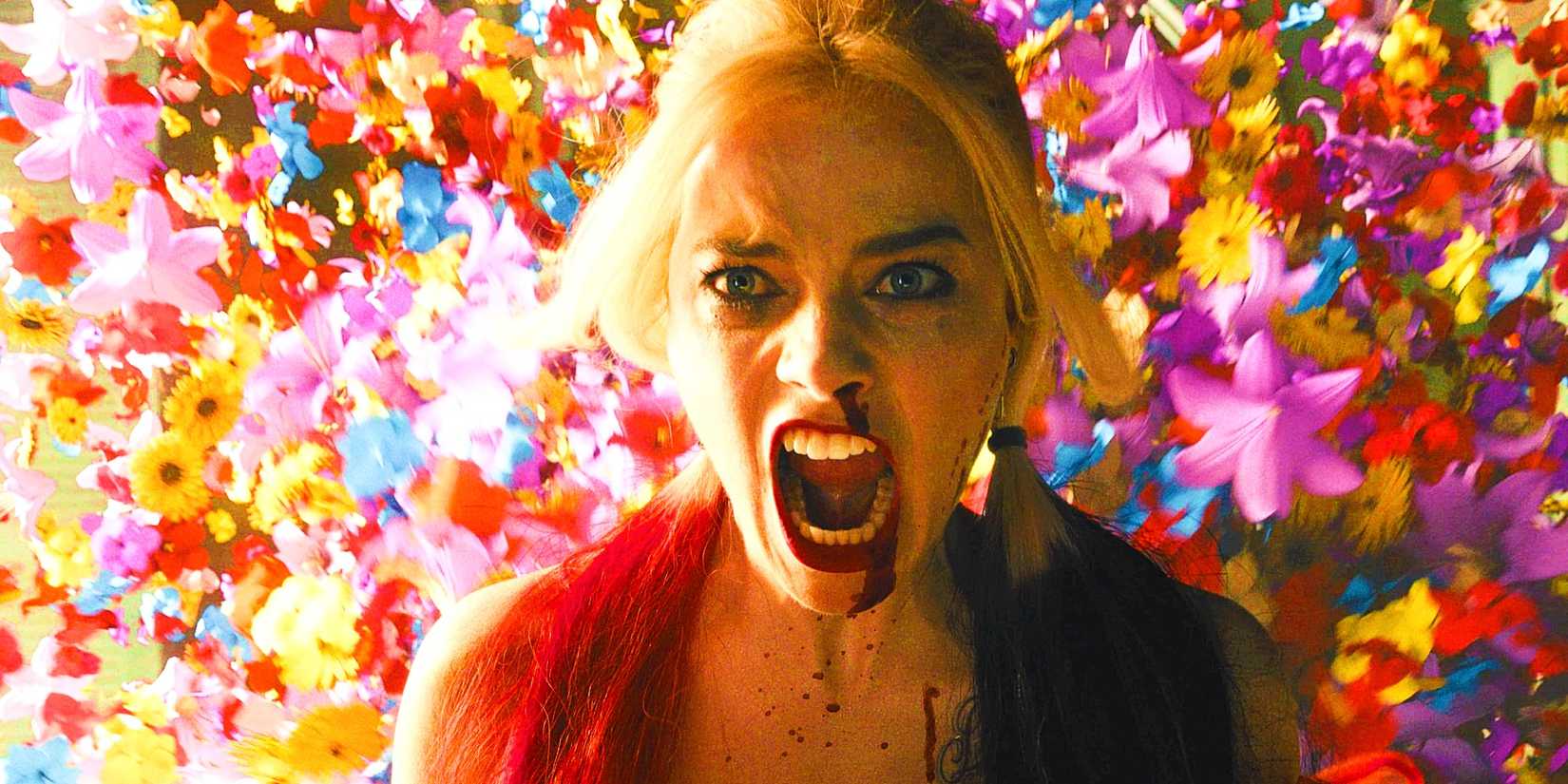 Margot Robbie como Harley Quinn gritando em frente a flores explodindo em O Esquadrão Suicida