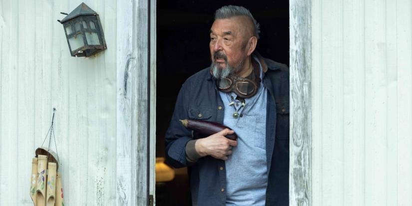Maximus Fixico (Graham Greene) holding an eggplant and looking out his door in Reservation Dogs.