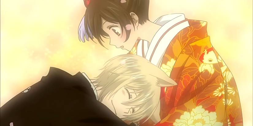 Nanami looks down as a smiling Tomoe hugs her from Kamisama Kiss.