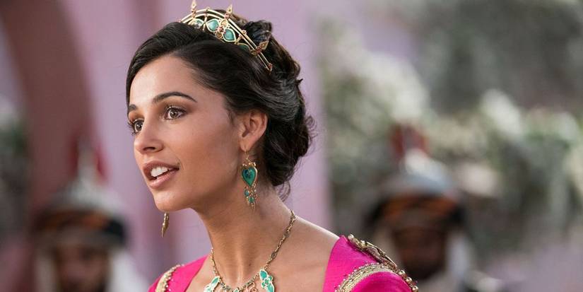Naomi Scott as Princess Jasmine smiles as someone in Aladdin (2019).