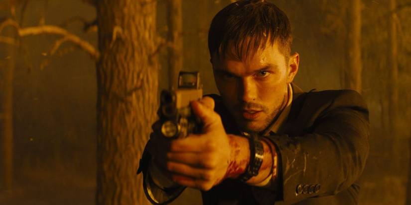 Nicholas Hoult como Patrick aponta uma arma para Hannah em uma floresta em chamas em Those Who Wish Me Dead.