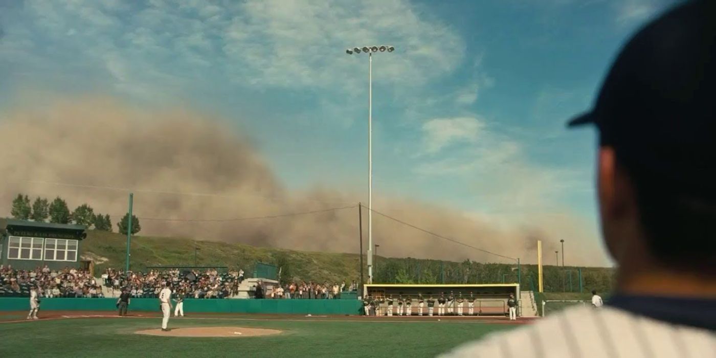 Players standing on a baseball field as a sand storm approaches in Interstellar