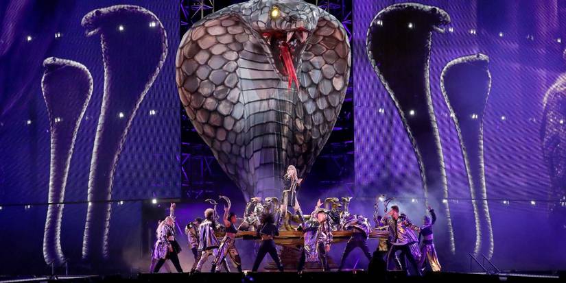 Taylor Swift cantando em frente a uma cobra gigante com dançarinos de fundo em Taylor Swift Reputation Stadium Tour