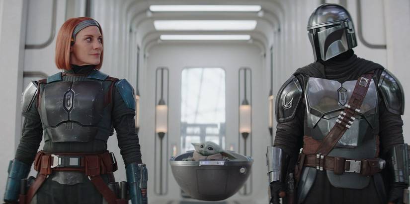 Bo-Katan and Din Djarin look at each other with Grogu in his floating carrier between them