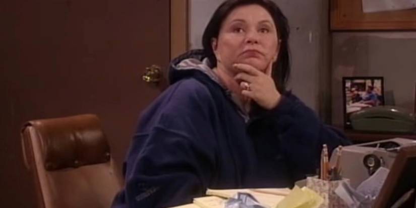 Roseanne sentada em sua mesa escrevendo no episódio 9 de Roseanne, 'Into That Good Night'.