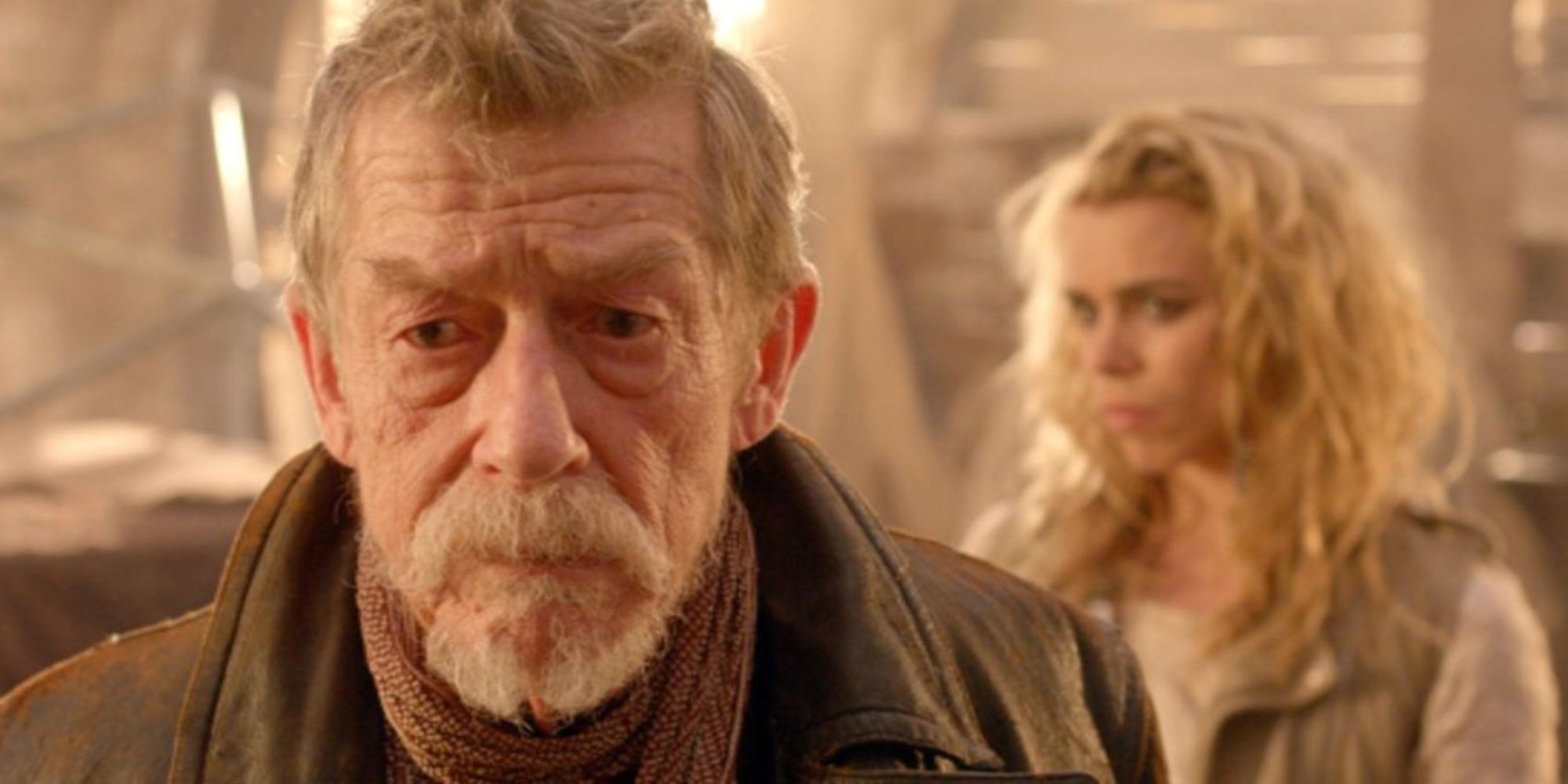 John Hurt as the War Doctor looking serious with Billie Piper as Bad Wolf over his shoulder