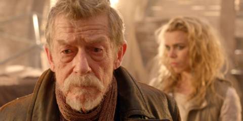 John Hurt as the War Doctor looking serious with Billie Piper as the Moment over his shoulder in the Doctor Who episode 