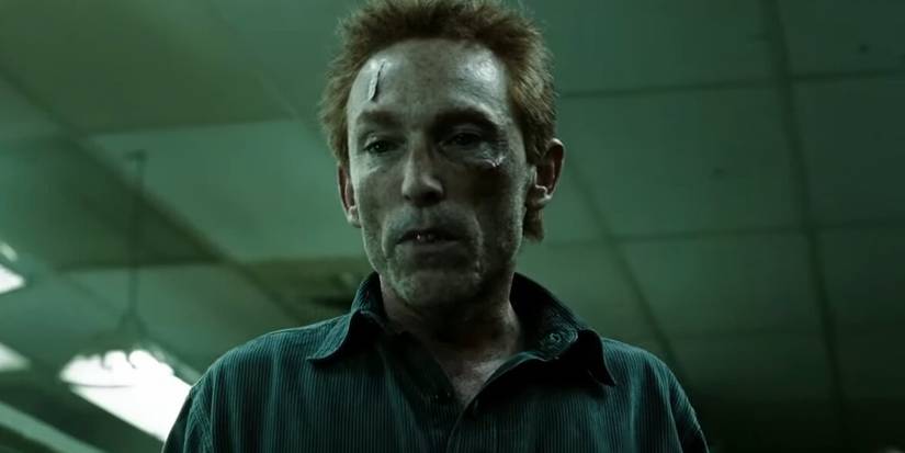 Jackie Earle Haley como Rorschach esperando na fila por comida na prisão em Watchmen