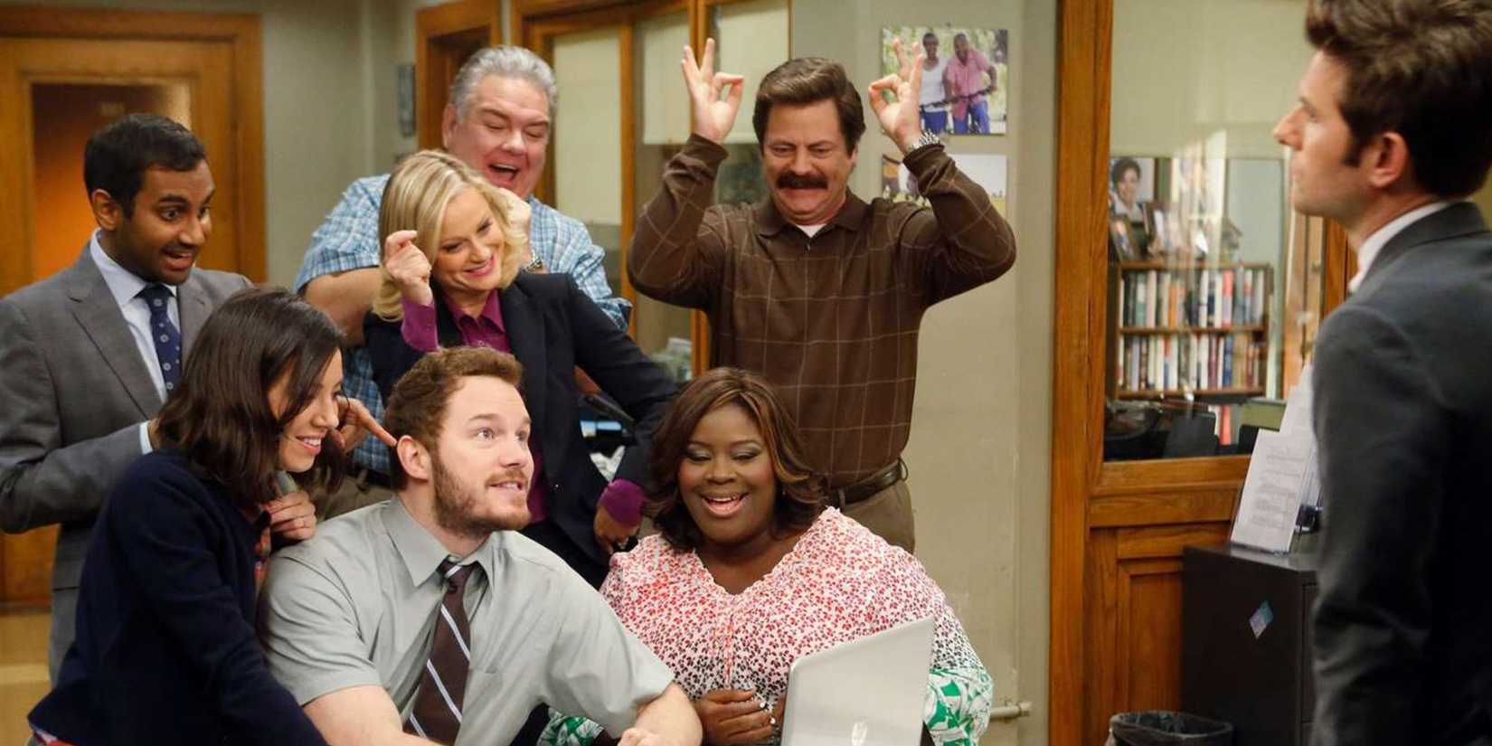 O elenco de Parks and Recreation celebrando em seu escritório