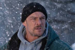 Alan Ritchson stands in the snow in Ordinary Angels