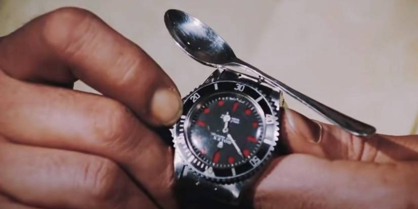 Close up of James Bond's (Roger Moore) hands using his magnetic watch to attract a nearby spoon in Live and Let Die.