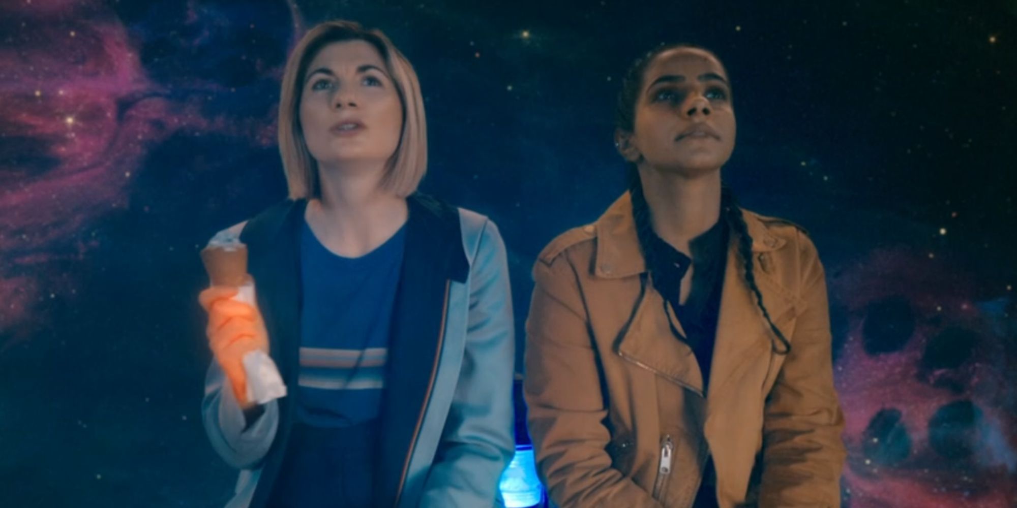 Jodie Whitaker as the Thirteenth Doctor and Mandip Gil as Yazmin Khan sitting together and looking up in Doctor Who