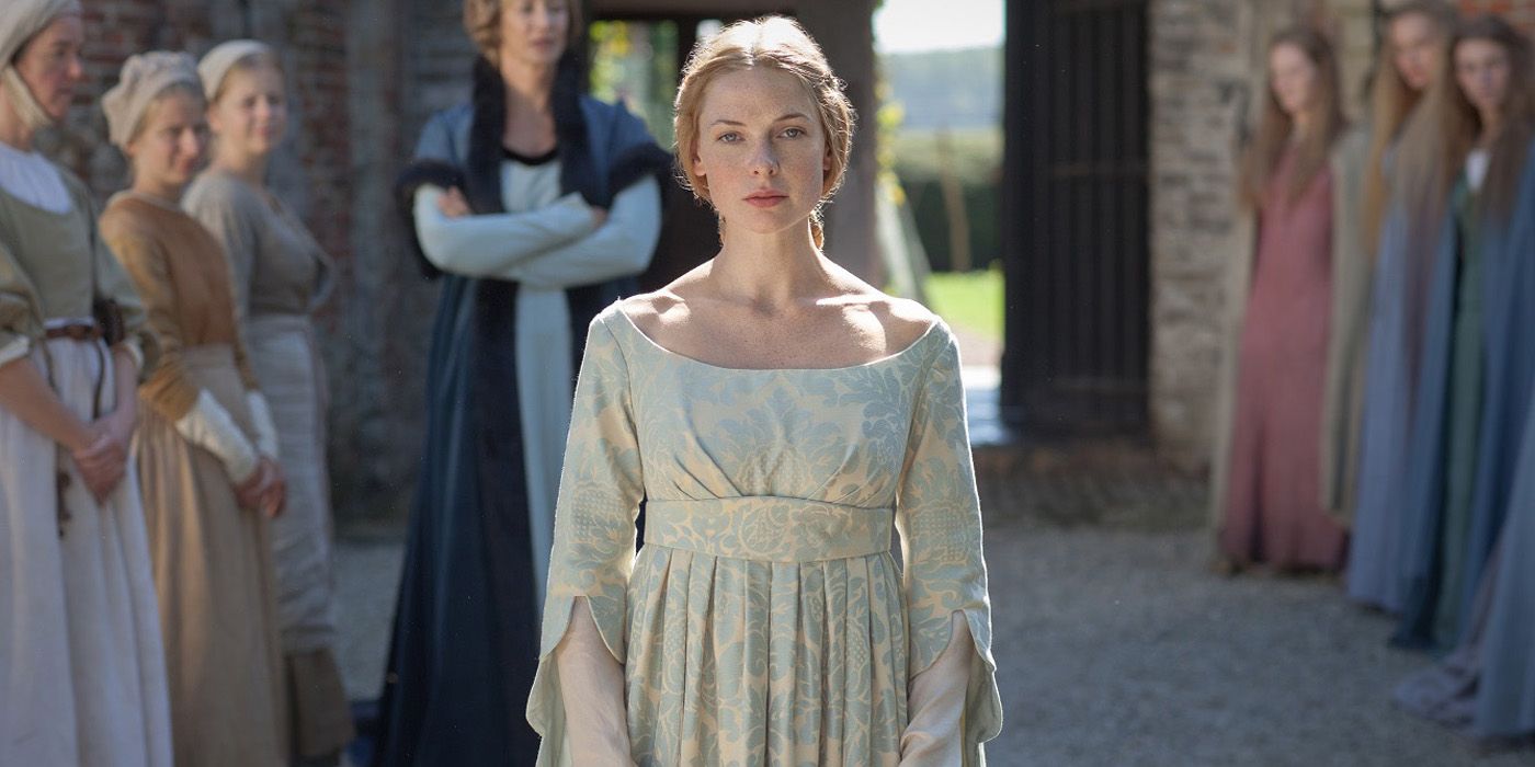 Rebecca Ferguson como Elizabeth Woodville caminhando por uma fila de mulheres do lado de fora em The White Queen