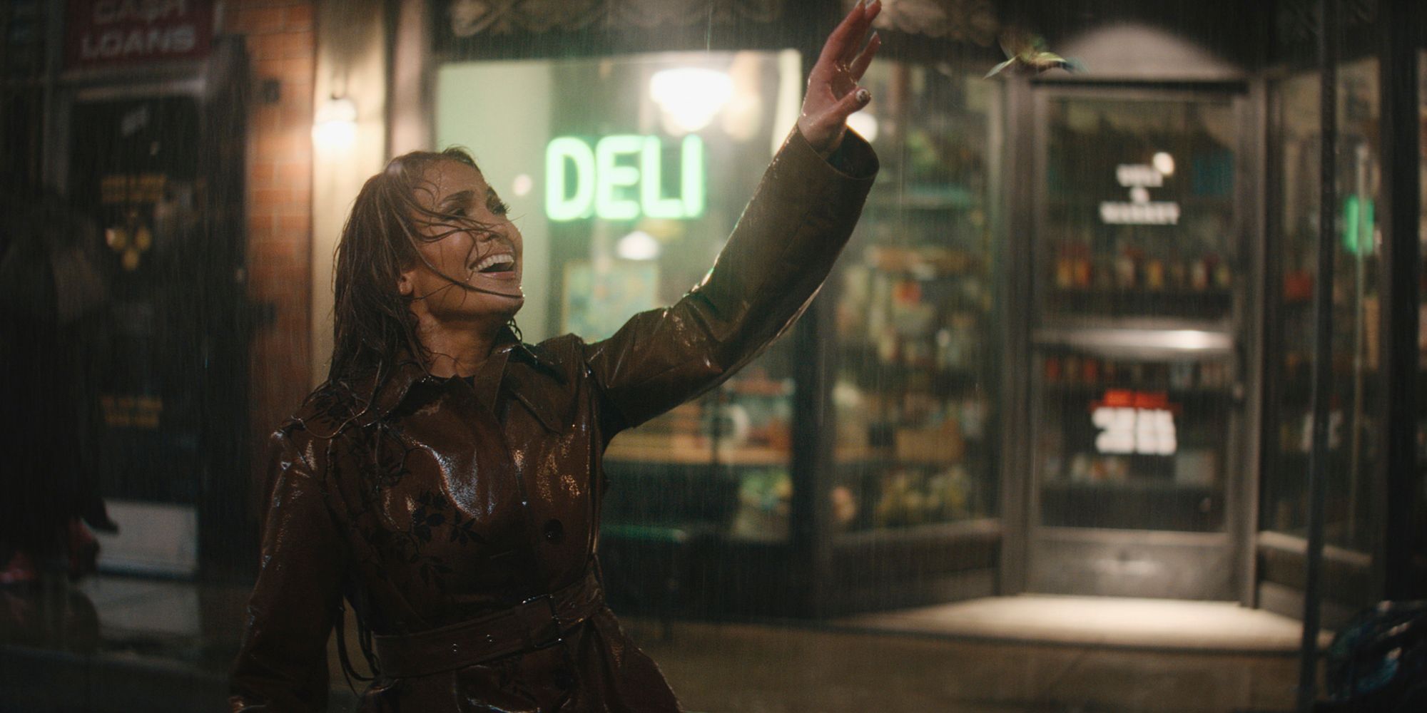 jennifer lopez standing outside a deli and touching the rain in this is me now