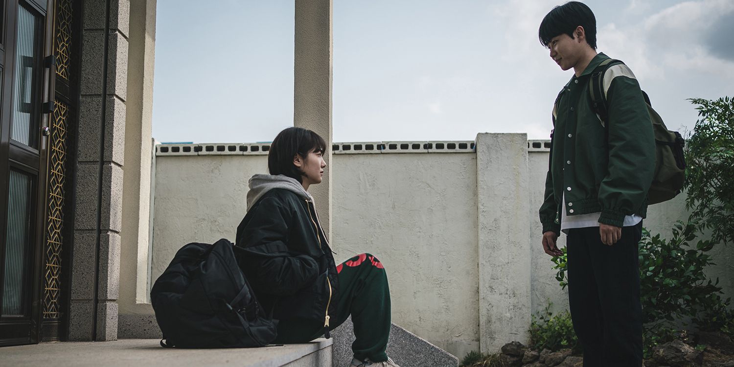 Jian sitting on steps and Jungmin standing in front of her in A Shop For Killers episode 1