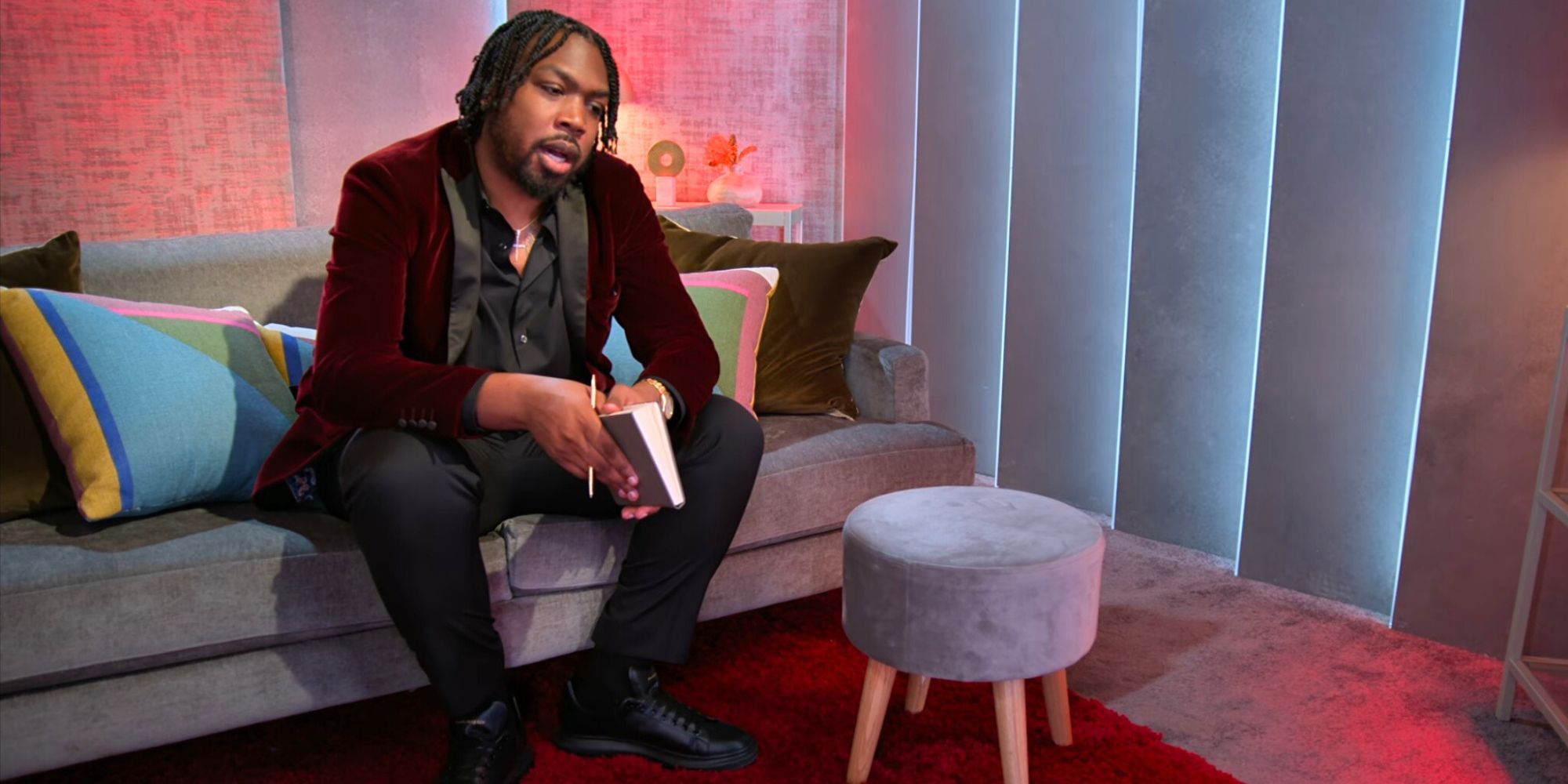 Kenny Love Is Blind season 6 sitting on couch in pods leaning forward holding a notebook