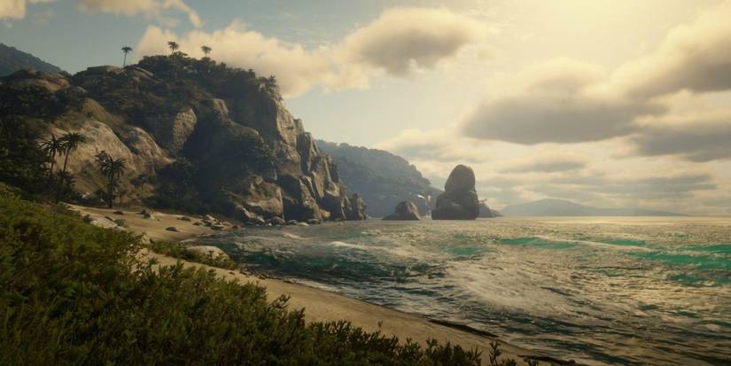 The rocky cliffs and sandy beaches of Guarma's shoreline near dusk in a screenshot from Red Dead Redemption 2.