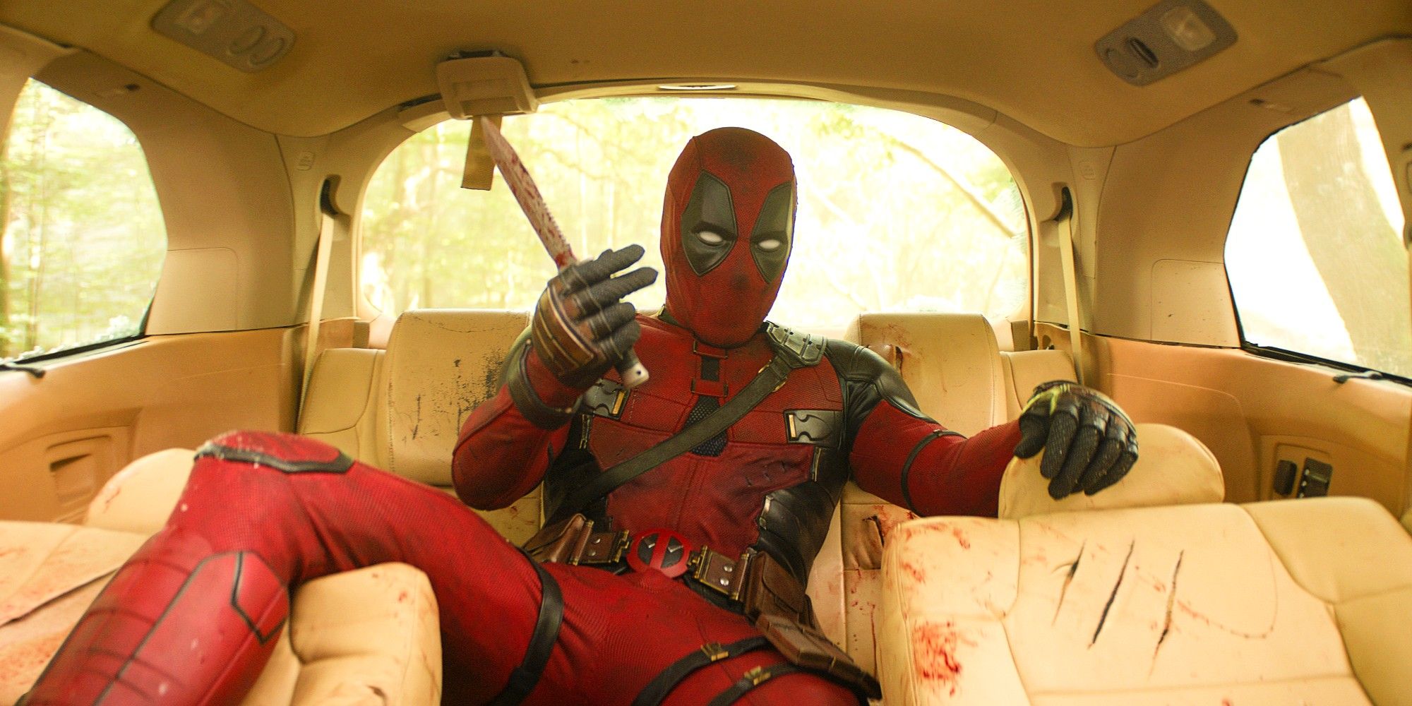 Ryan Reynolds como Deadpool esparramado no banco de trás de um carro coberto de arranhões sangrentos em Deadpool e Wolverine
