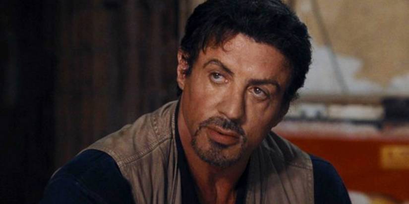 Sylvester Stallone como Barney Ross, com expressão séria em Mercenários.