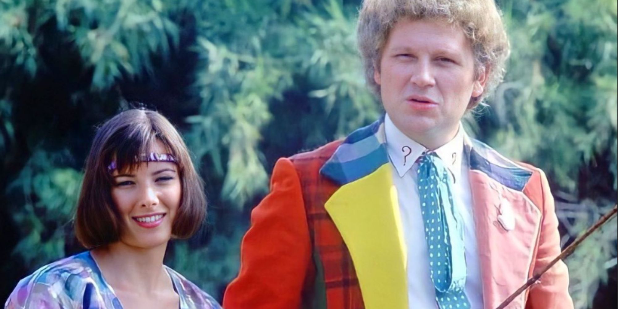 Nicola Bryant as Peri Brown smiling alongside a serious looking Colin Baker as the Sixth Doctor in Doctor Who