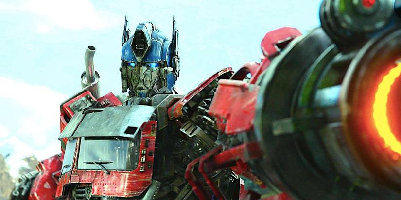 A grimacing Optimus Prime points a cannon at the viewer in 'Transformers: Rise of the Beast'