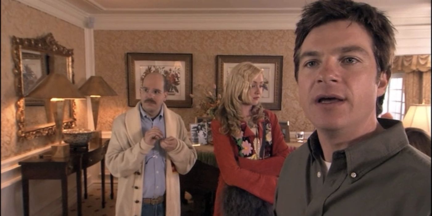 Michael looking off at something and talking while Tobias and Linsday stand behind him at Lucille's penthouse in Arrested Development's pilot.