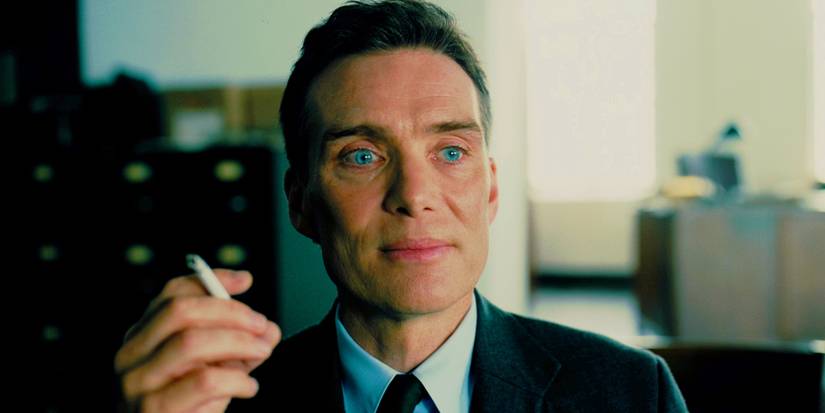 Cillian Murphy as J Robert Oppenheimer smoking a cigarette and smiling in Oppenheimer
