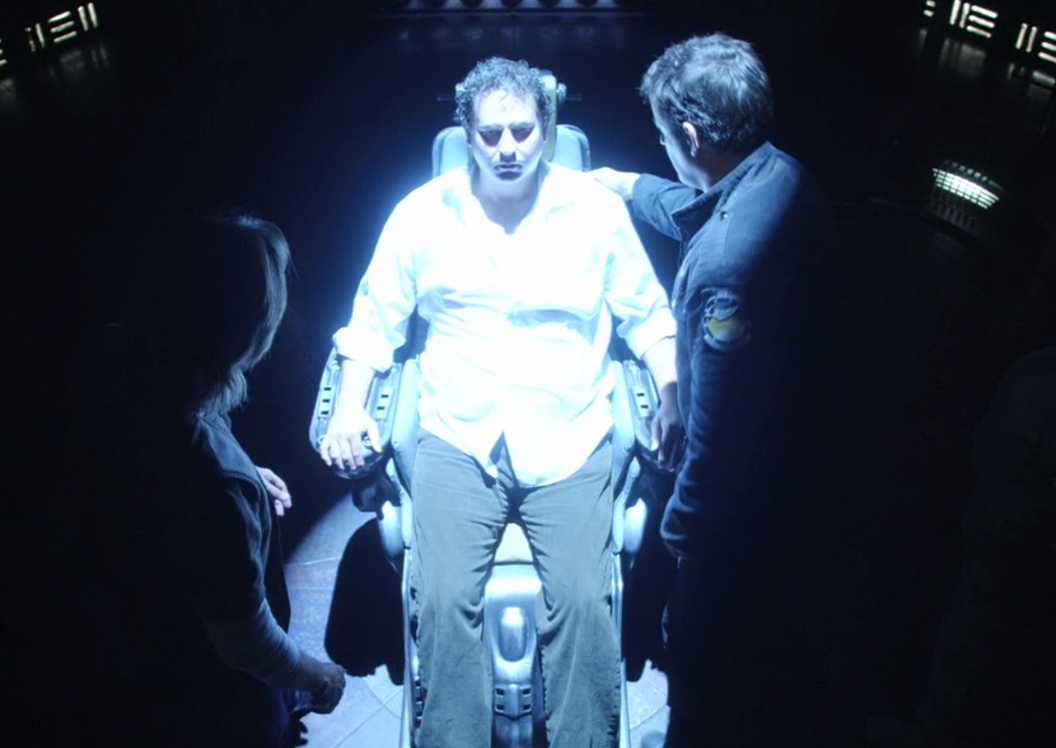 Dr. Jeremy Franklin sits in the chair with two other people looking at him in Stargate Universe