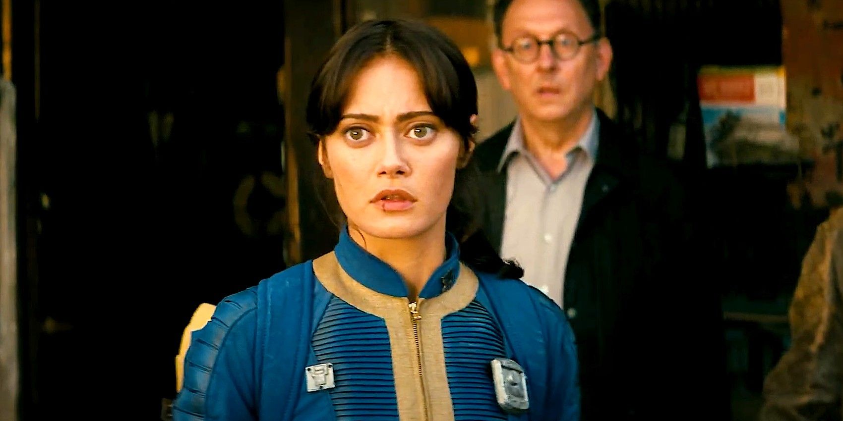 Ella Purnell's Lucy, wearing a gold and blue suit, looks worried in Fallout show