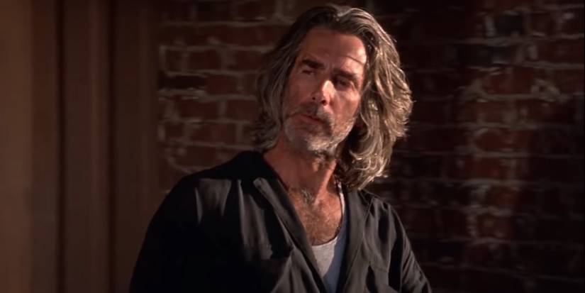Wade Garrett (Sam Elliott) looks on at a fight while going to the back of the Double Deuce in Road House 1989
