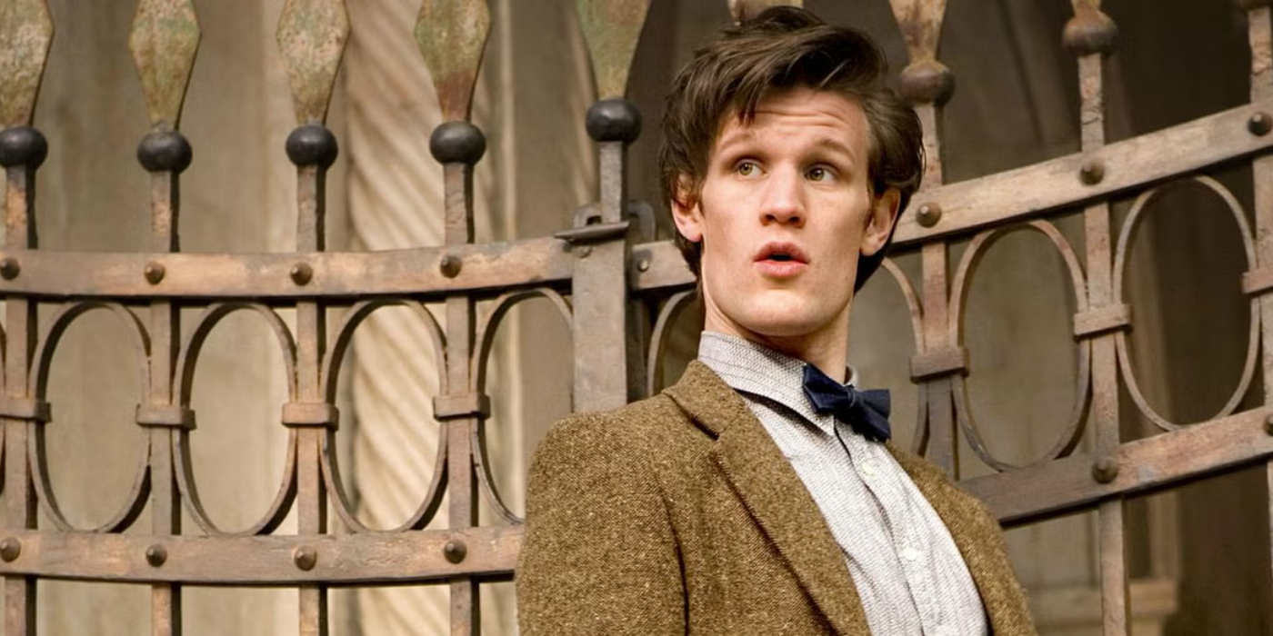 Matt Smith as 11th Doctor in front of a fence in Doctor Who 